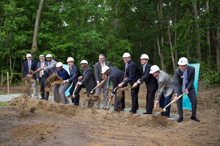 Row of people shoveling dirt