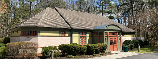 Photo of the exterior of Hidden Creek Recreation Center. The building is white bricks with green trim and red doors.