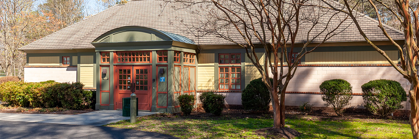Photograph of the exterior of Hidden Creek Recreation Center. The building is white with green trim and red doors.