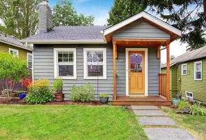 small gray house with a front porch and landscaping