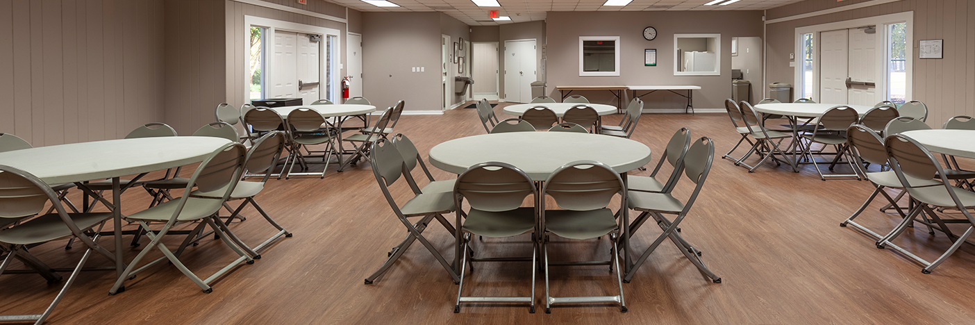 Interior of Hunton with round tables and chairs, view is towards the back of the room where the kitchen and restrooms are located.