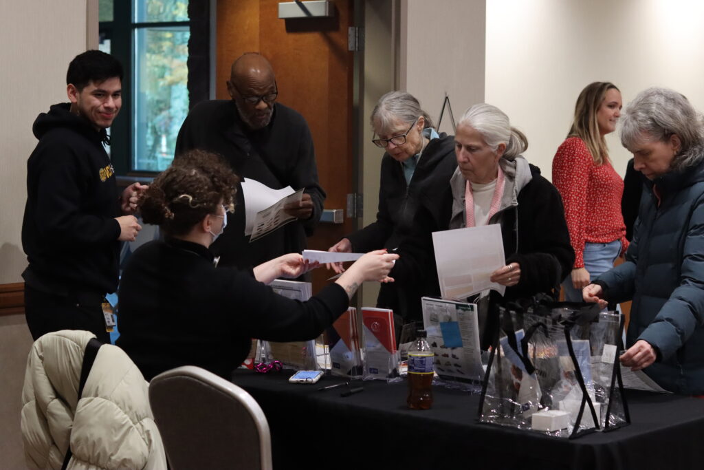 Three older people ask questions at a information fair.