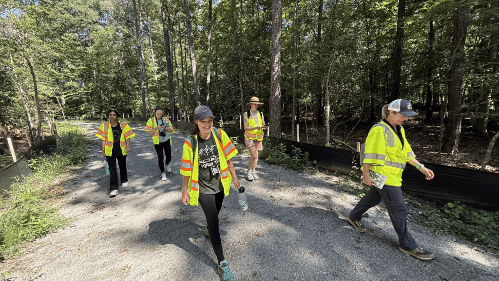 A photo of five people in yellow vests walking through the woods. 