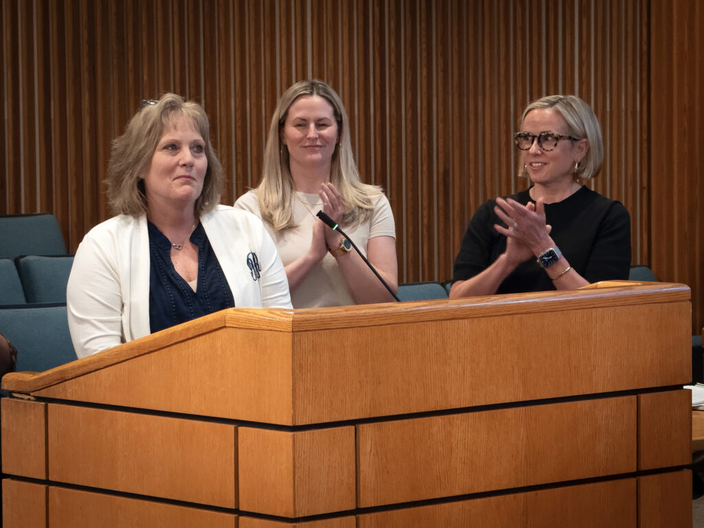 Officials from Human Resources stand at a lectern applauding Intern Coordinator Debbie Lumpkin.