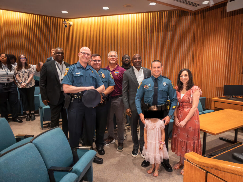 Officer Adam Marzullo and family and other police officers pose at the Board Meeting.