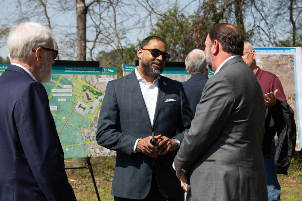 County and Wilton officials speak jovially in front of the proposed plans for the donated space
