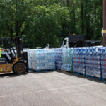 A forklift operator loads a pallet of bottled water at Best Plaza for distribution
