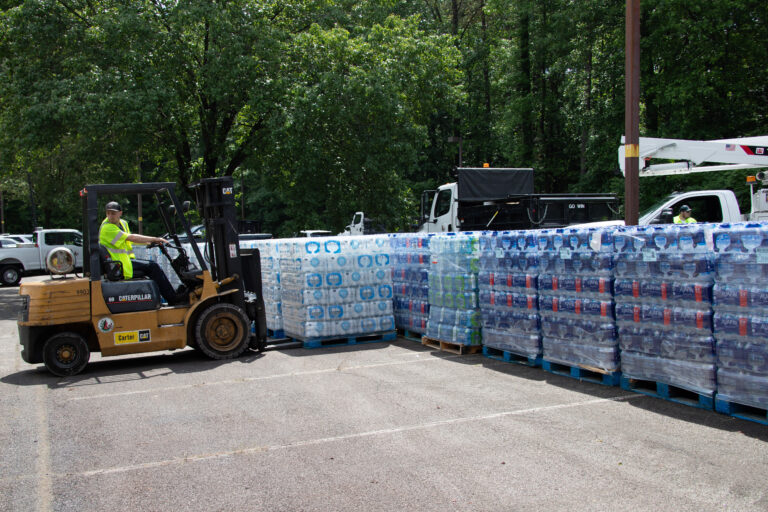 A forklift operator loads a pallet of bottled water at Best Plaza for distribution