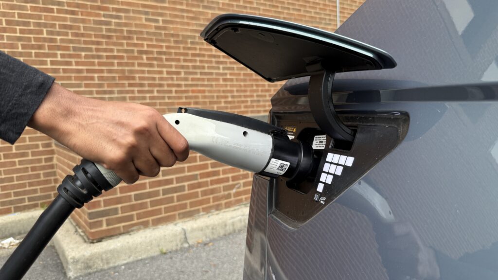 An image of a person plugging a charger into an electric vehicle.