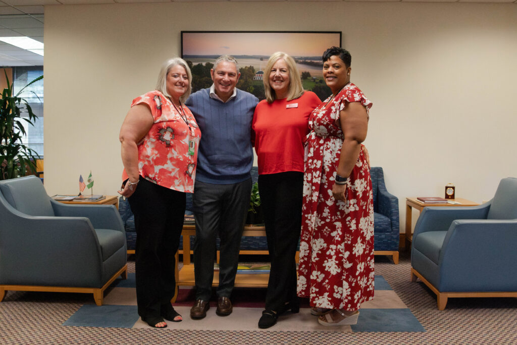 Three woman and one man pose for a photo.