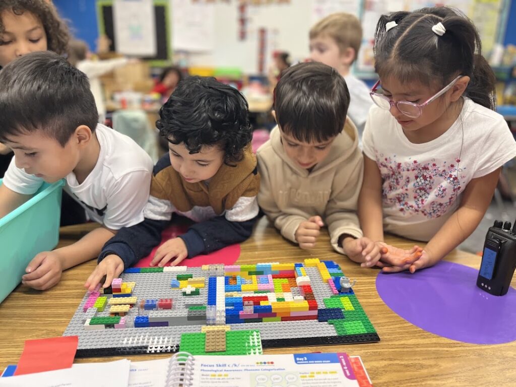 Young students make a demo school building out of blocks.