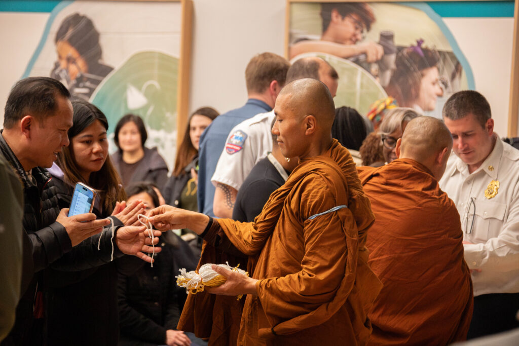 A photo of a monk who gives a peace bracelet to a man in a crowd of other supporters.