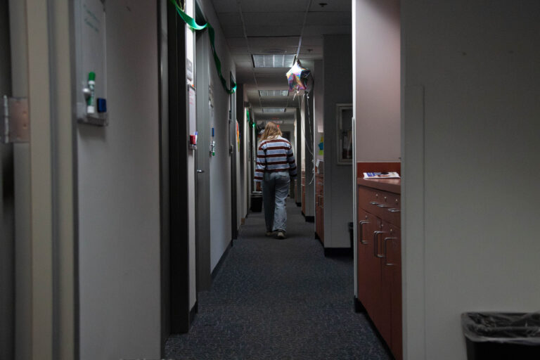A person walks down a narrow, dimly-lit hallways,
