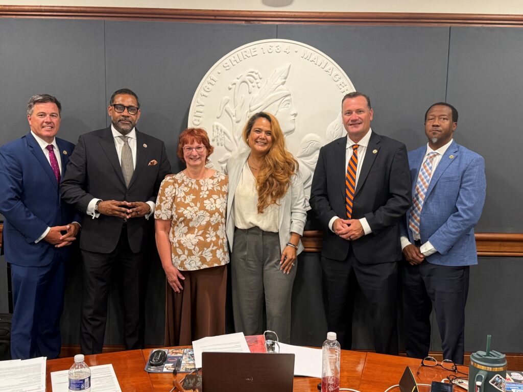 A woman stands with the five members of the Board of Supervisors in front of a large county seal.