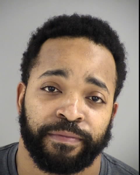 Image shows a Black male with short curly hair and a black beard.