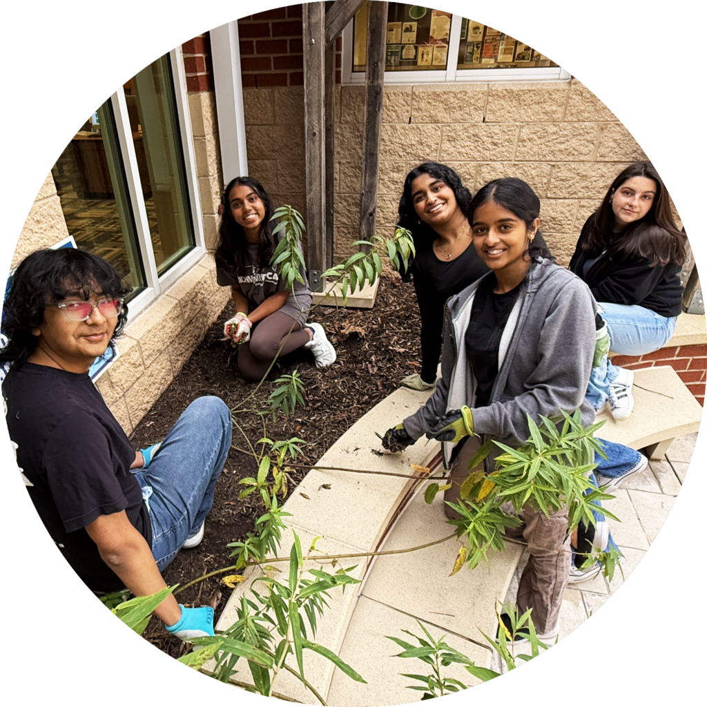 Five Henrico students are posing while planting a garden.