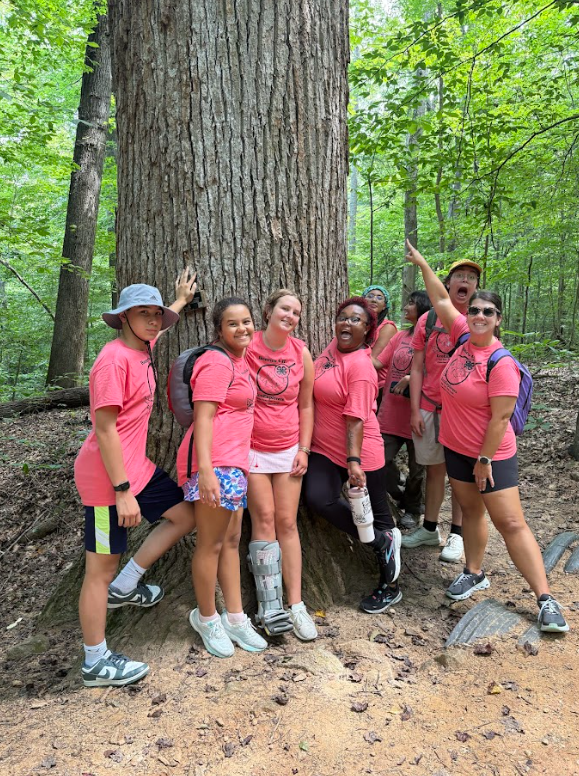 Group of students standing at the base of a large tree.