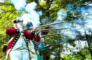 Revolutionary War reenactors firing muskets for a demonstration at Red, White, and Lights event. 