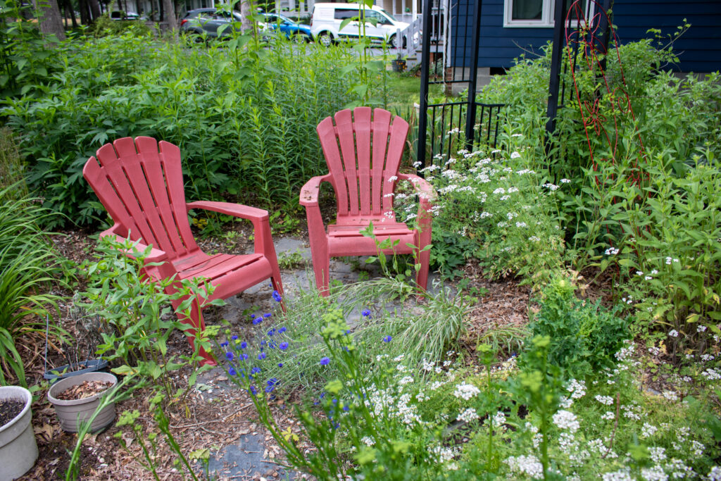 photo of two red lawn chars surrounded by a garden of thriving plants