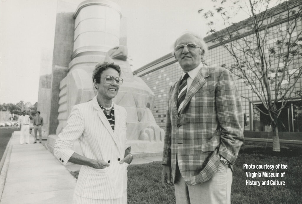 A man and woman stand in front of a large eagle sculpture.