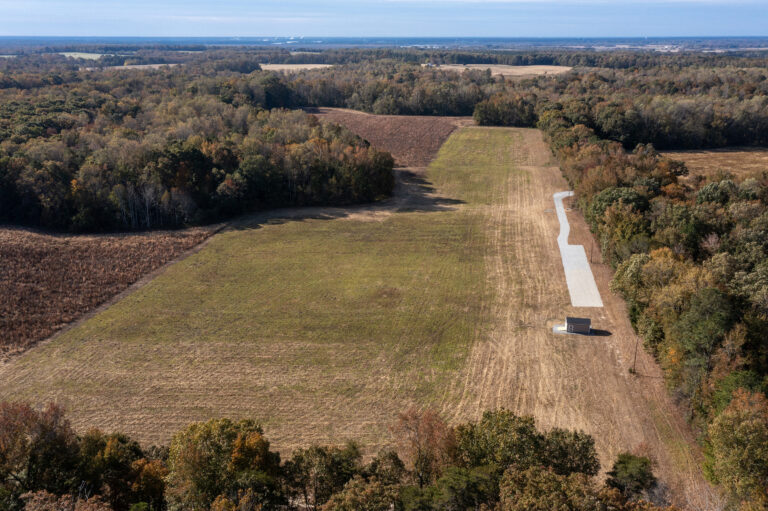 Aerial photo of open land at Runnymeade Farm with a small building and a driveway leading to it.