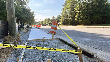 A partially finished new sidewalk with a caution tape