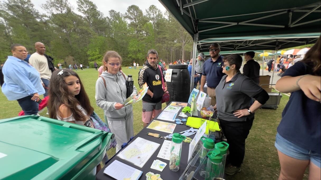 People standing and talking at a vendor tent at Earth Day