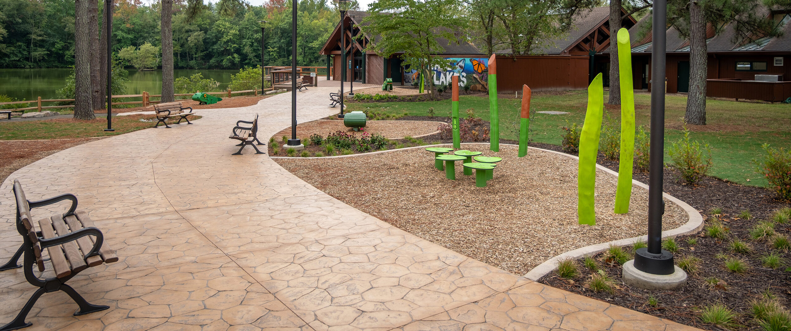 Photo of the Three Lakes Park renovated building with a hand painted sign, benches and colorful play area.
