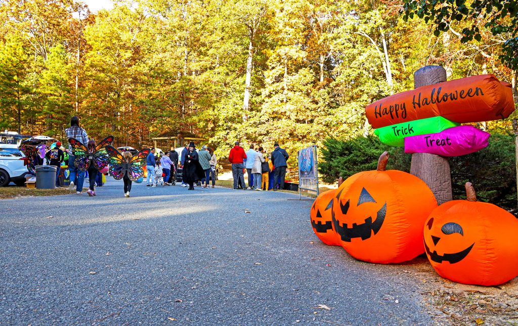 People walking around at Trunk or Treat and a sign that says Happy Halloween.