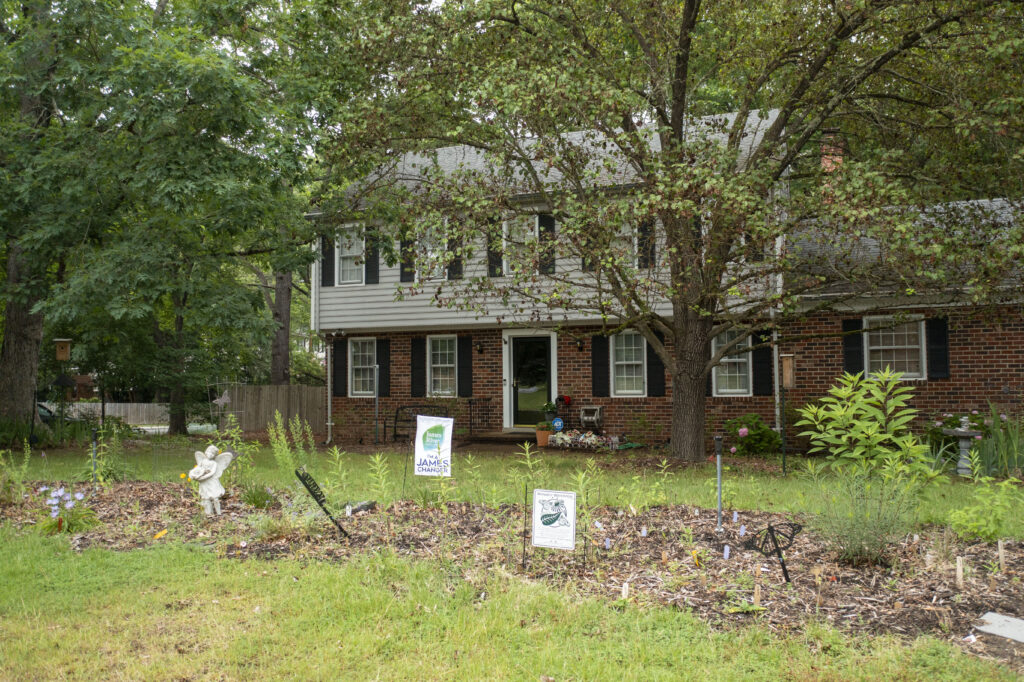 photo of a house with a large tree and large garden bed in the front yard