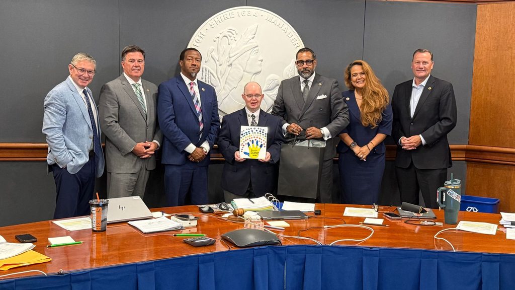 From left to right photo shows: County Manager John Vithoulkas, Tuckahoe District Supervisor Jody Rogish, Varina District Supervisor Tyrone Nelson, Thomas Gardner, who's holding a painting of a hand print that says Down Syndrome Awareness Month, Fairfield District Supervisor and Board Chair Roscoe Cooper, Three Chopt District Misty Roundtree and Brookland District Supervisor Daniel Schmitt.