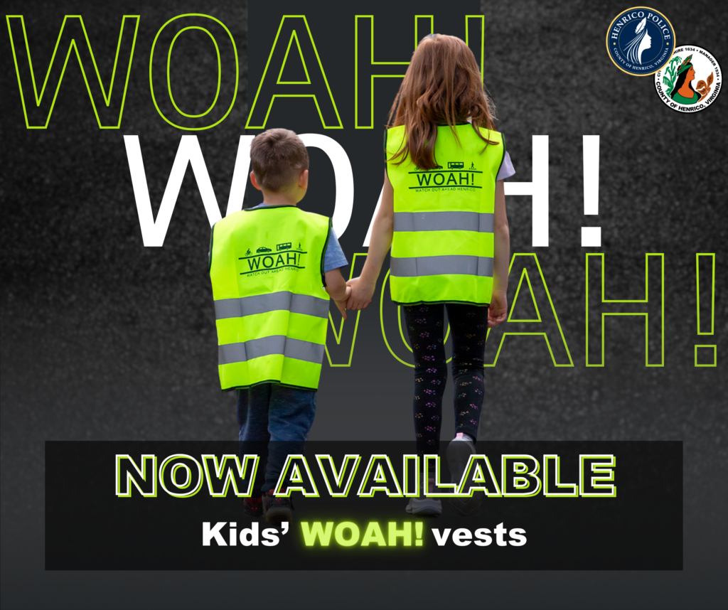 Image is of two children holding hands wearing a WOAH! children's sized reflective vest