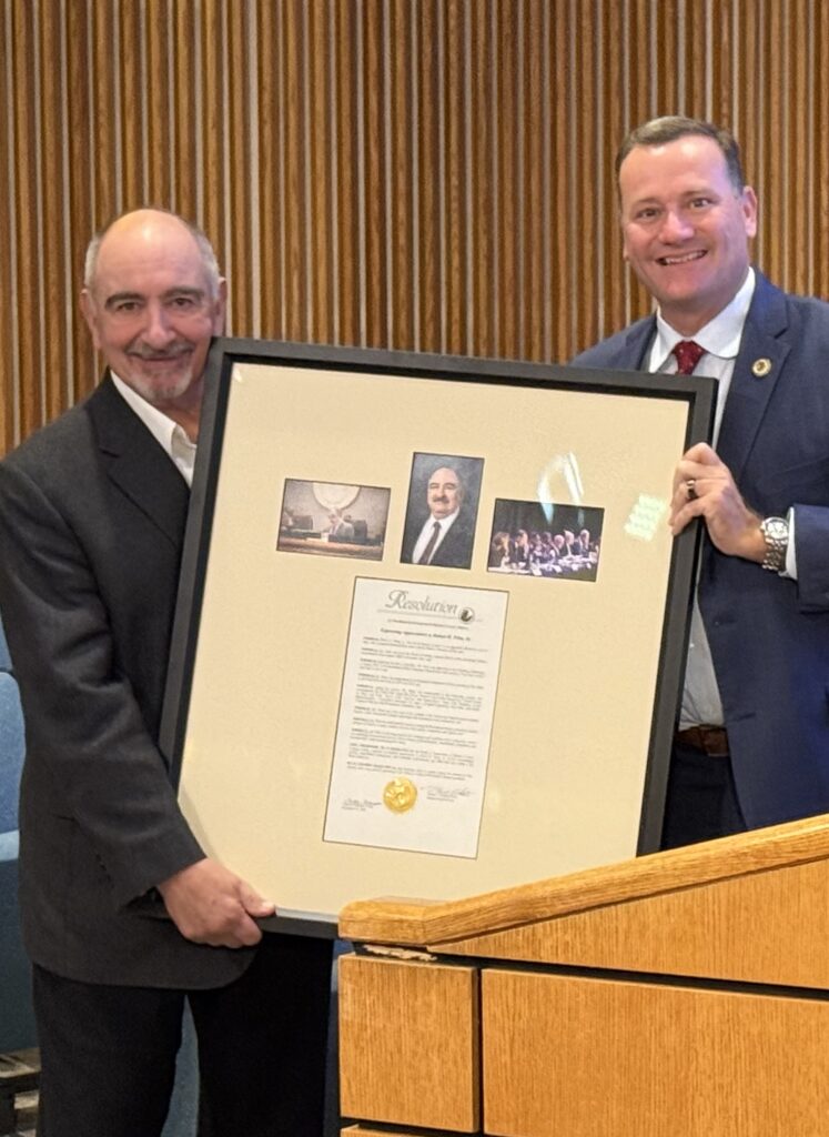 A man holds a framed photo and document.