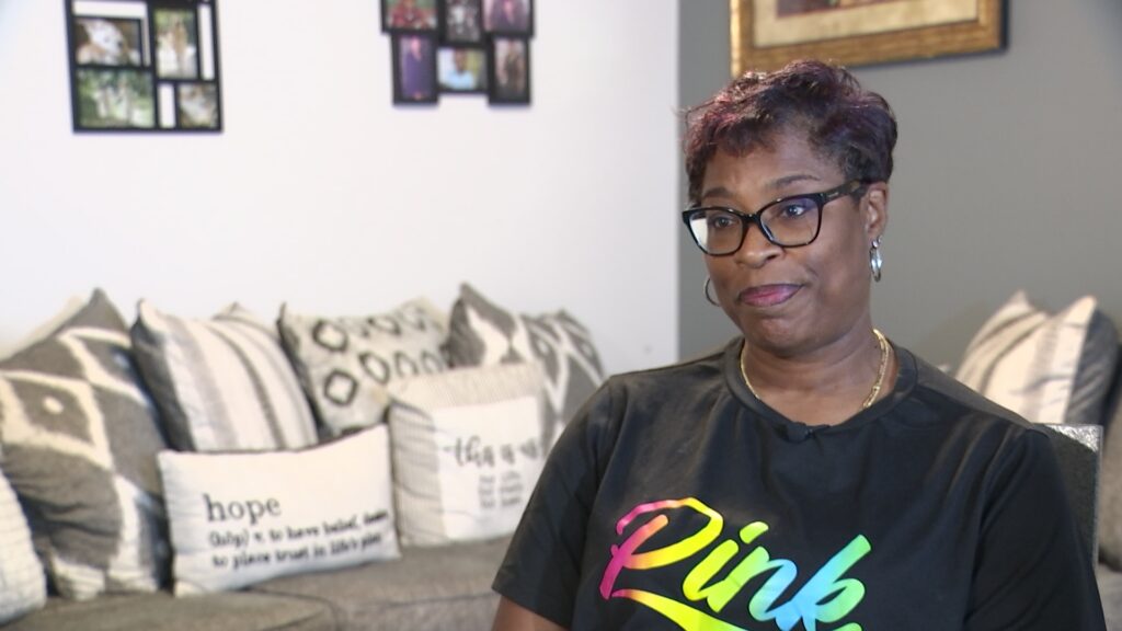 Image shows Yvettrise Hoskie sitting in her living room.
