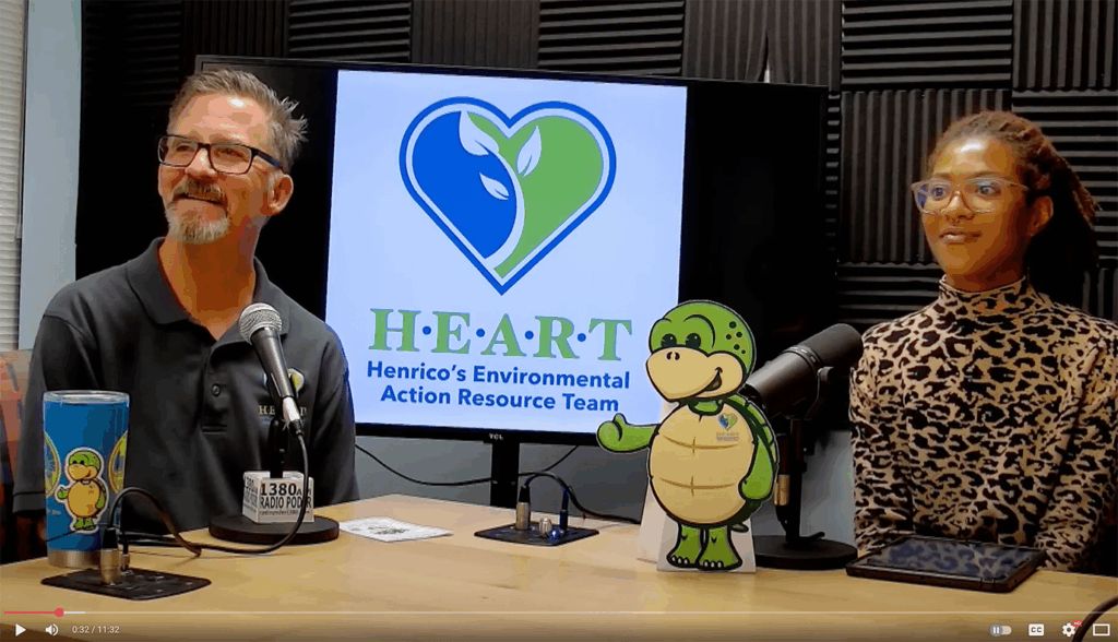 Two people sit in front of microphones for a podcast for HEART, Henrico's Environmental Action Resource Team. A cup and cutoff show a turtle mascot.