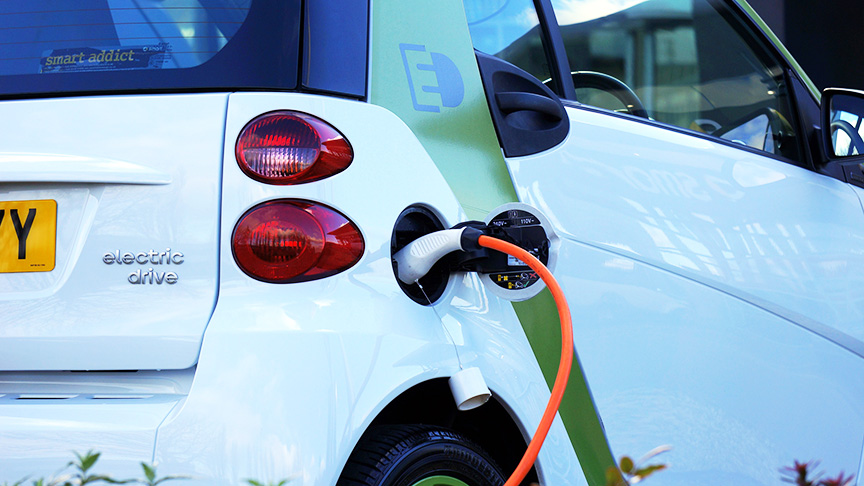 Photo of an white Electric Car with charging cord plugged in