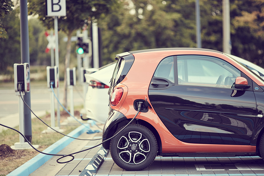 Photo of an orange Electric Car plugged into a charging station