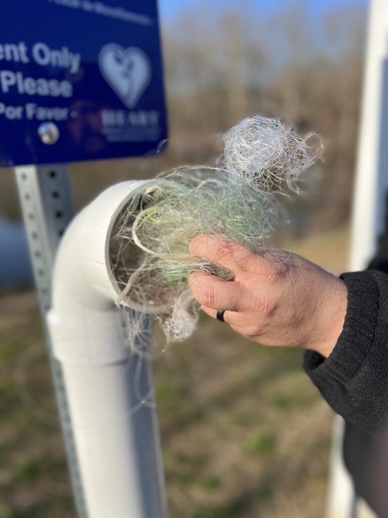 Close up of hand placing used fishing line into recycling station.