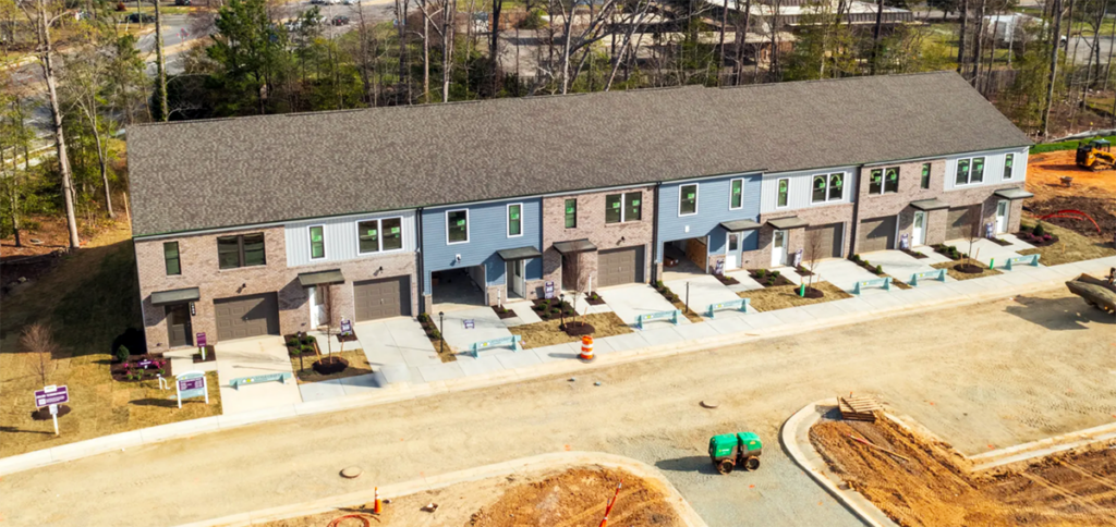 A row of multicolored townhomes, under construction.