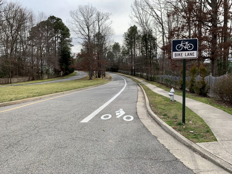 Picture of a road with a striped bike lane and bike lane sign