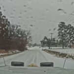 Photo from the view of a snowy road from a truck window.