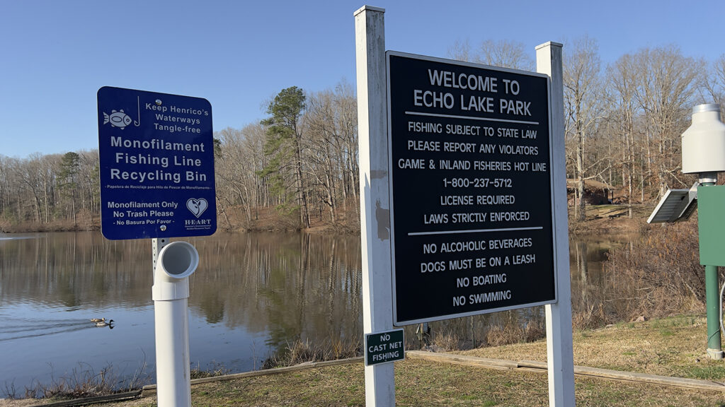 Two information signs in front of a lake.